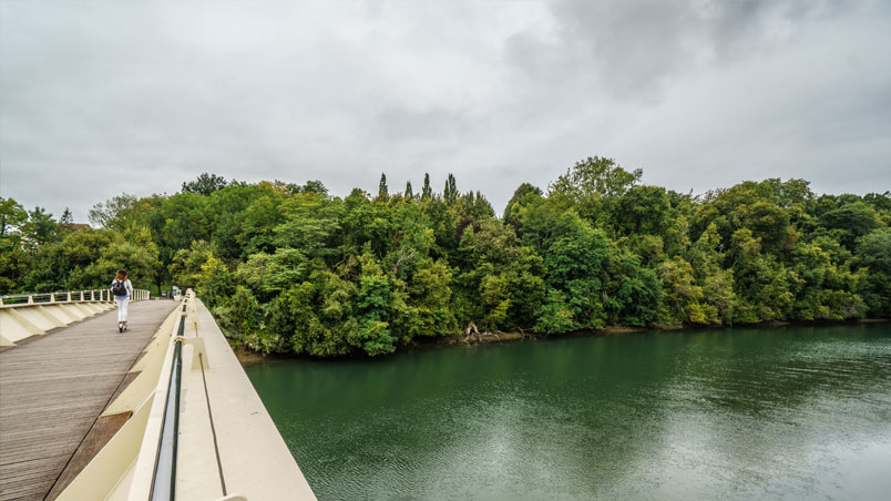 Femme traversant la passerelle Mikel Laboa sur un scooter électrique en direction du parc Cristina Enea